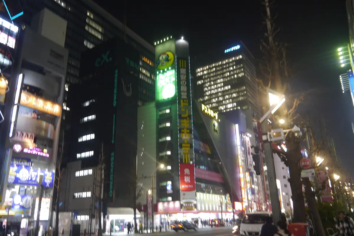 A busy Akihabara street at night, with illuminated signs on tall buildings and traffic below